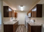 Thumbnail 11 of 19 - Grand Forks, ND Grandview Apartments. A kitchen with white appliances and wood floors.