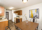 Thumbnail 5 of 19 - Grand Forks, ND Grandview I Apartments. a kitchen and dining area with a four chair table and art on the wall