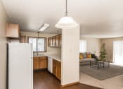 Thumbnail 6 of 28 - A kitchen with white appliances and living room with a couch and a coffee table in the background at Harrison and Richfield, Grand Forks, North Dakota