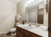 Thumbnail 14 of 28 - Grand Forks Harrison Apartments. A bathroom with a sink and a toilet and a mirror