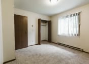 Thumbnail 12 of 28 - Grand Forks Harrison Apartments. A bedroom with a window and a door to a closet