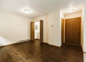 Thumbnail 10 of 28 - Grand Forks Harrison Apartments. A living room of an empty apartment with wood flooring and a wooden door