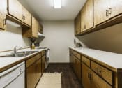 Thumbnail 9 of 28 - Grand Forks Harrison Apartments. kitchen with wooden cabinets and white appliances and a sink