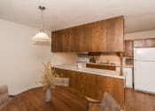 Thumbnail 4 of 12 - Grand Forks Kremer Apartments. A dining room with a four-chair table and a kitchen in the background