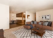 Thumbnail 1 of 12 - Grand Forks Kremer Apartments .a living room with a brown couch and a wooden coffee table with a kitchen and dining area in the background