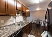 Thumbnail 3 of 20 - Grand Forks, ND Library Lane Apartments a kitchen with brown cabinets and granite countertops