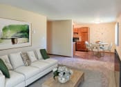 Thumbnail 3 of 12 - a living room with a couch and a coffee table in front of a dining room. Grand Forks, ND Madison Apartments