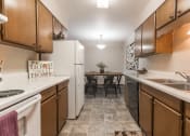 Thumbnail 3 of 16 - Grand Forks, ND Mayfair Apartments a kitchen with wooden cabinets and white appliances