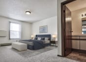 Thumbnail 7 of 25 - Grand Forks Primrose Apartments. A bedroom with a bed and a chair in a room