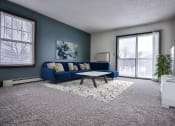 Thumbnail 6 of 25 - Grand Forks Primrose Apartment.  A living room with a blue couch and coffee table in front of a sliding glass door