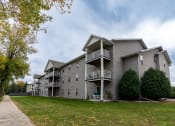 Thumbnail 1 of 25 - Grand Forks, ND Primrose Court Apartments. Exterior of a three level building with balconies and patios