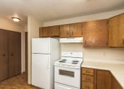 Thumbnail 7 of 10 - Grand Forks Ridgemont Apartments. A kitchen with white appliances and a closet in the background.