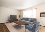 Thumbnail 3 of 23 - Grand Forks, ND Riverwood Apartments. A living room with a couch and a chair and a television