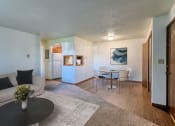 Thumbnail 6 of 19 - Grand Forks, ND Roughrider Apartments. a living room with a couch table and chairs and a kitchen in the background