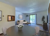 Thumbnail 3 of 19 - Grand Forks, ND Roughrider Apartments. a dining area with a table and chairs and a couch in the background