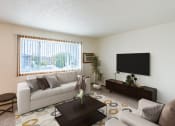 Thumbnail 1 of 22 - A living room of an apartment with a white couch and a television. Grand Forks, ND Southview Apartments.