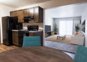Thumbnail 6 of 27 - Grand Forks, ND Sunview apartments. A dining room with a table with four blue chairs and a living room in the background