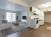 Thumbnail 2 of 27 - Grand Forks, ND Sunview apartments.  a living room with a couch, coffee table, tv, and a glass sliding door. A kitchen to the right