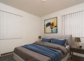 Thumbnail 5 of 6 - Grand Forks, ND Valley Home Duplex. a bedroom with two windows and a bed with a gray blanket and blue pillows