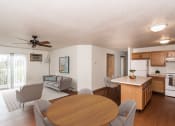 Thumbnail 3 of 10 - Grand Forks, ND Vista Apartments. A living room and dining room with a couch, chair, and table with the kitchen in the background.