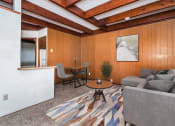 Thumbnail 2 of 8 - Grand Forks, ND Washington Apartments a living room with wood paneling and a beamed ceiling with a couch and dining area in the background