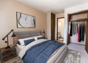 Thumbnail 1 of 7 - a bedroom with a bed and a closet with clothes in it
