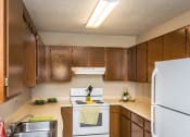 Thumbnail 7 of 19 - Grand Forks, ND Grandview I Apartments. a kitchen with white appliances and wooden cabinets