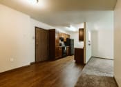 Thumbnail 6 of 17 - Grand Forks, ND Grandview II Apartments. A kitchen with black appliances and wood floors with a dining room and living slightly in shot.
