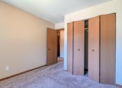 Thumbnail 8 of 12 - Grand Forks, ND Madison Apartments. A bedroom with a closet and carpeted floors.
