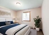 Thumbnail 2 of 7 - a bedroom with a bed and a plant and a window. Bismarck, ND Hannifin Apartments