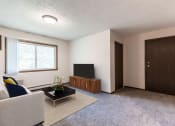 Thumbnail 1 of 7 - an empty living room with a couch and a television. Bismarck, ND Hannifin Apartments