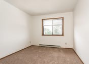 Thumbnail 16 of 28 - Grand Forks Harrison Apartments. A bedroom with carpet and a window