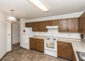 Thumbnail 15 of 28 - Grand Forks Harrison Apartments. A kitchen with white appliances and wooden cabinets