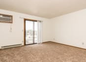 Thumbnail 8 of 28 - Grand Forks Harrison Apartments. An empty living room with a sliding glass door to a balcony