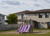 Thumbnail 14 of 14 - a playground with a set of slides in front of a house. Fargo, ND Hazelwood Townhomes