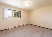 Thumbnail 7 of 10 - an empty room with carpet and a window. Bismarck, ND Highland Meadows Apartments