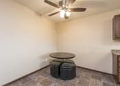 Thumbnail 3 of 10 - a living room with a ceiling fan and a table with two stools. Bismarck, ND Highland Meadows Apartments