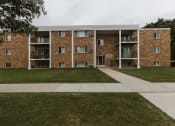 Thumbnail 1 of 2 - Grand Forks, ND Hoven Lane Apartments. an exterior view of a brick apartment building with grass and a sidewalk