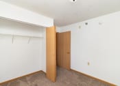 Thumbnail 19 of 23 - an empty bedroom with a closet and a door to the bathroom. Hutchinson, MN Deer Park Apartments
