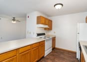 Thumbnail 16 of 23 - an empty kitchen with white appliances and wooden cabinets. Hutchinson, MN Deer Park Apartments
