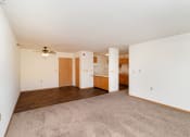 Thumbnail 14 of 23 - an empty living room with a ceiling fan and a kitchen. Hutchinson, MN Deer Park Apartments