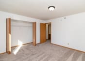 Thumbnail 10 of 23 - an empty living room with carpet and a door to a closet. Hutchinson, MN Deer Park Apartments