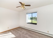 Thumbnail 11 of 23 - an empty living room with a ceiling fan and a window. Hutchinson, MN Deer Park Apartments