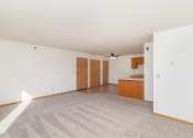 Thumbnail 6 of 23 - an empty living room and kitchen with white walls and carpet. Hutchinson, MN Deer Park Apartments