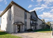 Thumbnail 22 of 23 - a brick apartment building with a sidewalk and grass. Hutchinson, MN Deer Park Apartments