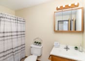 Thumbnail 10 of 11 - a bathroom with a toilet sink and mirror and a shower. Hutchinson, MN Echo Manor Apartments