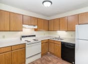 Thumbnail 8 of 18 - an empty kitchen with white appliances and wooden cabinets. Hutchinson, MN Twin Oaks Townhomes