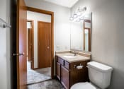 Thumbnail 15 of 16 - Bismarck, ND Eastbrook Apartments | A bathroom with a toilet sink and mirror