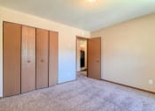 Thumbnail 9 of 12 - Grand Forks, ND Madison Apartments. A bedroom with a closet and carpeted floors.