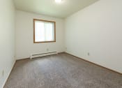 Thumbnail 22 of 34 - a bedroom with carpet and a window. Fargo, ND Islander Apartments